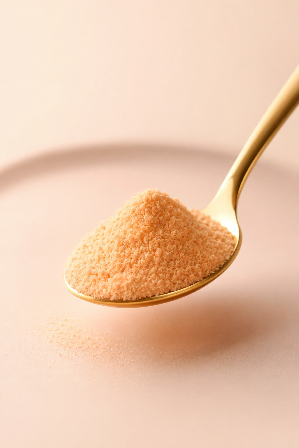 Peach wellness powder scooped on a polished gold spoon